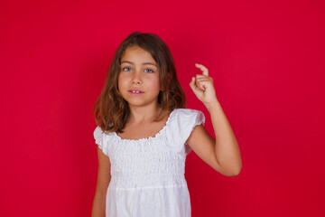 Little caucasian girl with blue eyes wearing white dress standing over isolated red background pointing up with fingers number nine in Chinese sign language Jiu