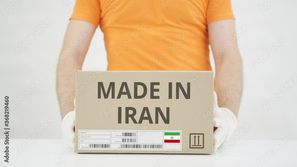 Poster worker wearing orange uniform puts box with made in iran print on the table