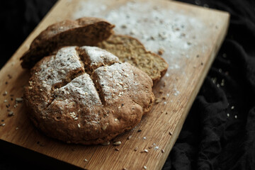 rye bread with seeds and a few sliced ​​pieces on a wooden board with flour and seeds close-up blurred background