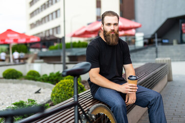 Enjoying the urban lifestyle. Young bearded man near his bicycle outdoors