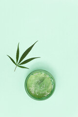 Cosmetics based on cannabis, jar with cream or gel for body and natural leaf of cannabis. Cosmetic product with hemp leaves. Flat lay with copy space.