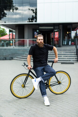 Enjoying his ride. Confident young bearded man looking forward while riding on his bicycle along the street