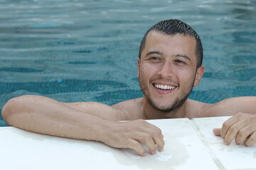 Handsome ethnic man smiling in swimming pool 