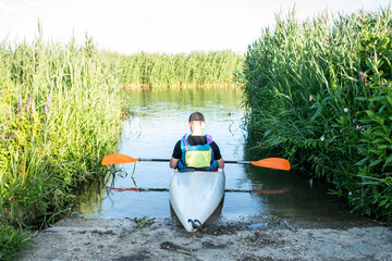 Male sat in a Kayak at a slip of a river ready to kayak downstream