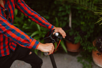 Closeup of hands of a young caucasian man with e scooter on the street