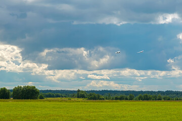 Plane towing a glider after takeoff with a left turn on a background of clouds
