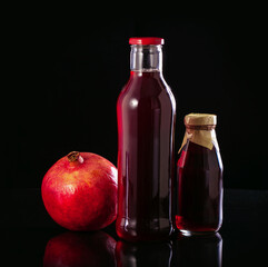 Fresh pomegranate juice in a bottle on black background.