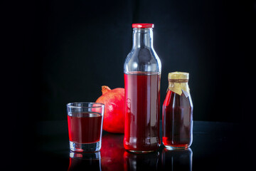 Pomegranate juice with fresh pomegranate fruit on black background.