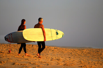 Surfeur, surfeuse sur la sable avec leur planche de surf
