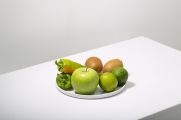 Fresh green vegetables and fruits on white table