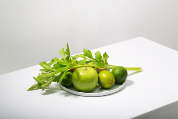 Fresh green vegetables and fruits on white table