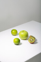 Fresh green fruits on white table, vertical orientation