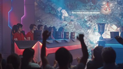 Two Esport Teams of Pro Gamers Play in RPG Strategy Video Game on a Championship Arena, Happy Red Team Wins Round and Celebrates with High-Fives.Big Screen Showing Mock-up Gameplay. Cyber Games Event