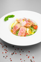 Tuna salad with egg, tomatoes and salad on a white plate. Lunch at the restaurant.