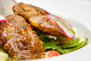 Grilled beef in a sauce with Dejon mustard and soft cheese in a case plate on a gray background.