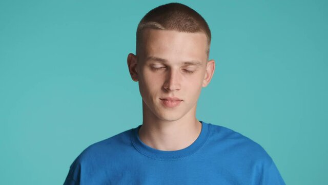 Portrait of handsome blue eyed blond guy intently looking in camera over colorful background