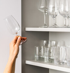Eine Hand stellt ein Glas in ein Regal. Jemand räumt auf und schafft Ordnung.