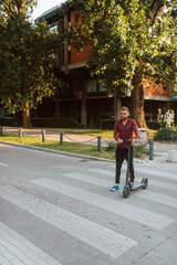 Full length of  handsome young bearded caucasian man on e scooter crosses a pedestrian  in the city