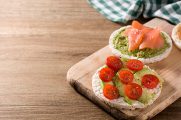 Assortment of ingredients on puffed rice cakes on wooden table. Copy space	