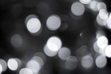 Blurred defocused lights dark gray black background. Abstract bokeh with soft light. Shiny festive christmas texture