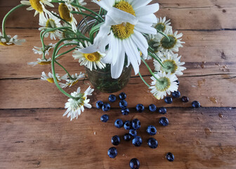 A still life of daisies and blueberries