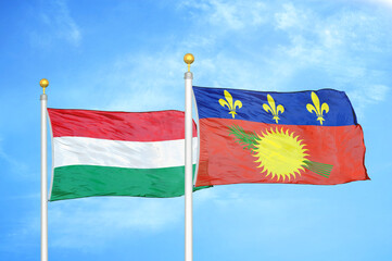 Hungary and Guadeloupe two flags on flagpoles and blue cloudy sky