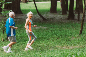 smiling elderly woman running with husband in park