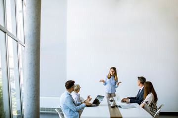 Group of business people with young adults and senior woman colleague on meeting at modern bright...
