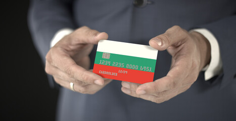 Businessman holding plastic bank card with printed flag of Bulgaria, fictional numbers