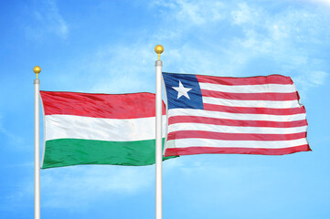 Hungary and Liberia two flags on flagpoles and blue cloudy sky