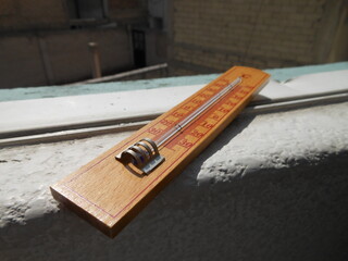 Wooden thermometer on a sunny window