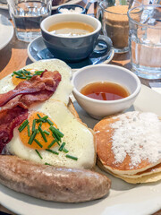 breakfast with egg, pancakes and sausage on table