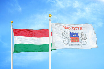 Hungary and Mayotte two flags on flagpoles and blue cloudy sky