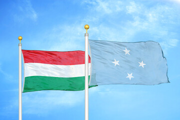 Hungary and Micronesia two flags on flagpoles and blue cloudy sky
