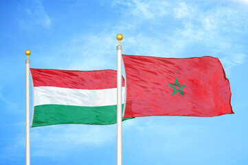 Hungary and Morocco two flags on flagpoles and blue cloudy sky