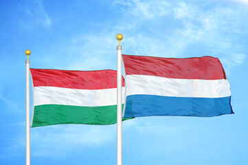 Hungary and Netherlands two flags on flagpoles and blue cloudy sky