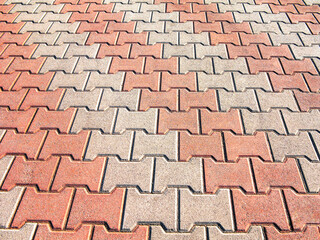 Decorative colorful sidewalk pavement. Tiled floor with grey tiles crossed by a diagonal double stripe of red tiles viewed at a low angle, full frame background pattern