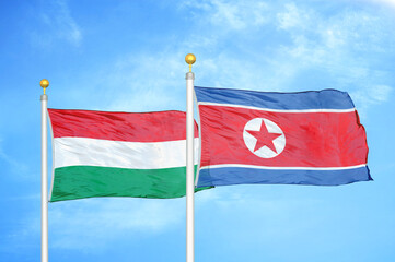 Hungary and North Korea two flags on flagpoles and blue cloudy sky
