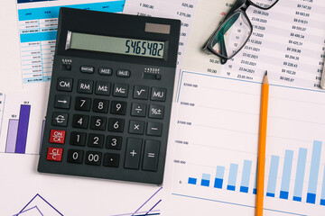 Desktop with a calculator, pencil, charts, documents and glasses. The concept of a business office. A top view of a flat layout.