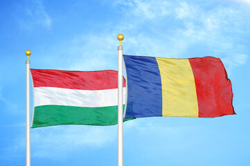 Hungary and Romania two flags on flagpoles and blue cloudy sky