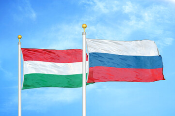 Hungary and Russia two flags on flagpoles and blue cloudy sky