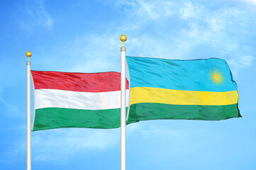 Hungary and Rwanda two flags on flagpoles and blue cloudy sky