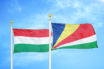 Hungary and Seychelles two flags on flagpoles and blue cloudy sky