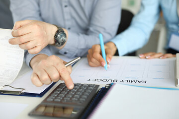 A couple in business clothes makes a family budget on paper. Reliable and functional personal finance management system