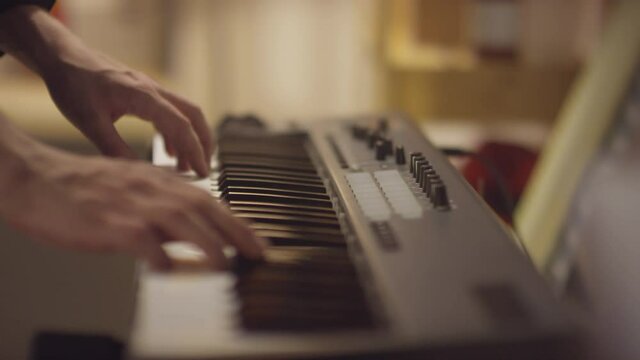 Close-up shot footage of unrecognizable musicians hands playing digital piano in studio