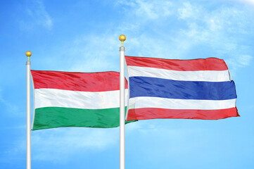Hungary and Thailand two flags on flagpoles and blue cloudy sky