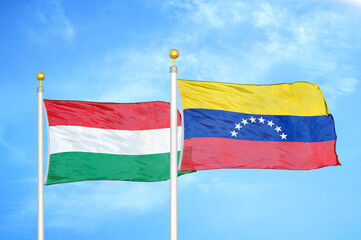 Hungary and Venezuela two flags on flagpoles and blue cloudy sky