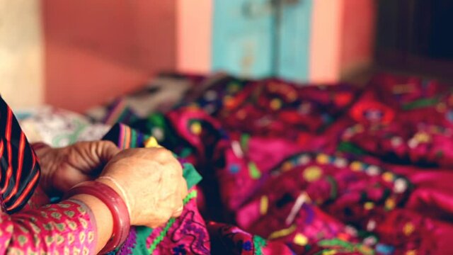 girl doing embroidery,Rajasthan or Gujarat embroidery artwork or handicrafts close-up views,selective focus,Kutchi Embroidery,
