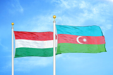 Hungary and Azerbaijan  two flags on flagpoles and blue cloudy sky