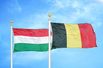 Hungary and Belgium  two flags on flagpoles and blue cloudy sky